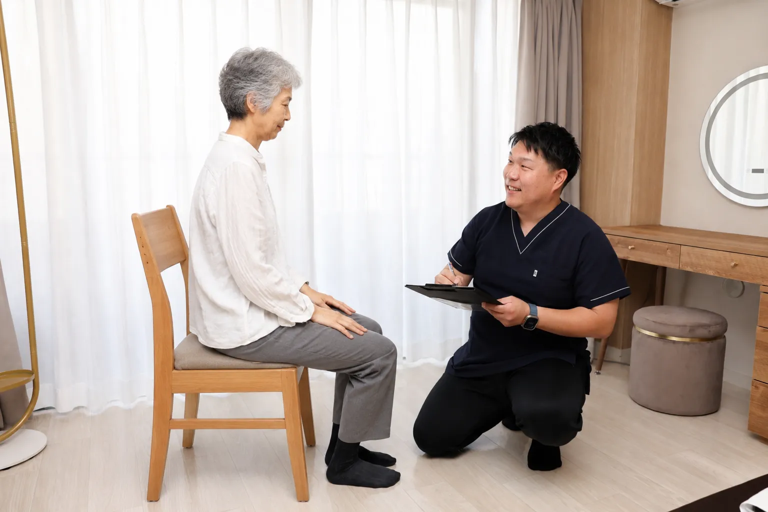 ご利用者と目線を合わせ、笑顔でお話を伺う院長