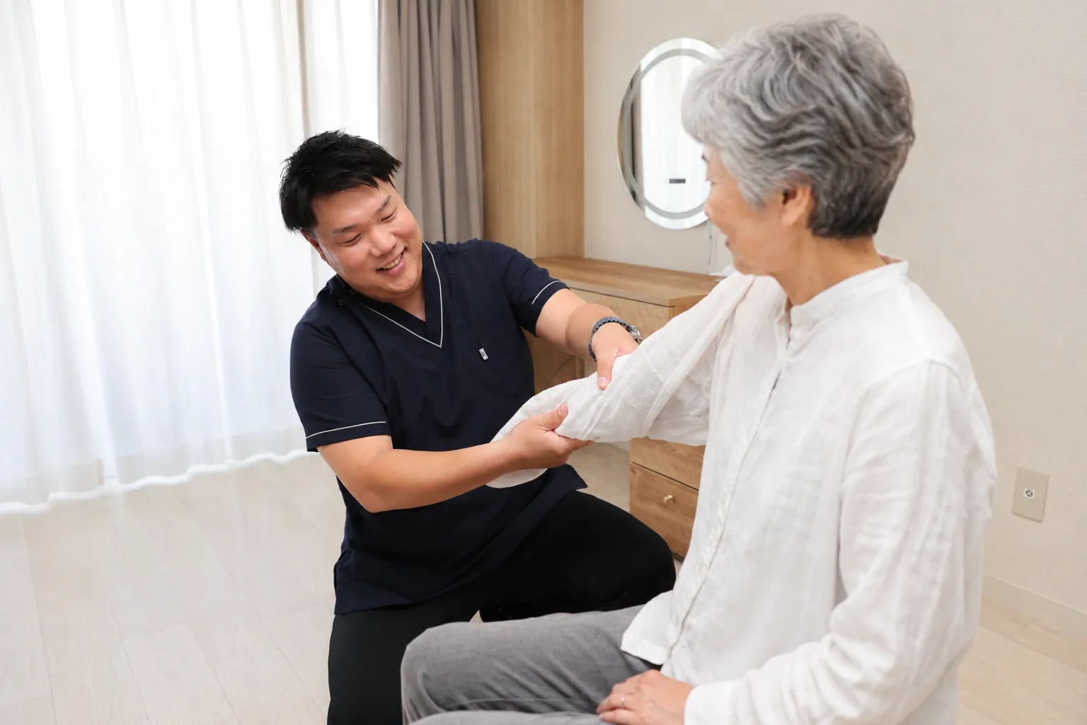 椅子に座るご利用者の前腕をマッサージする院長